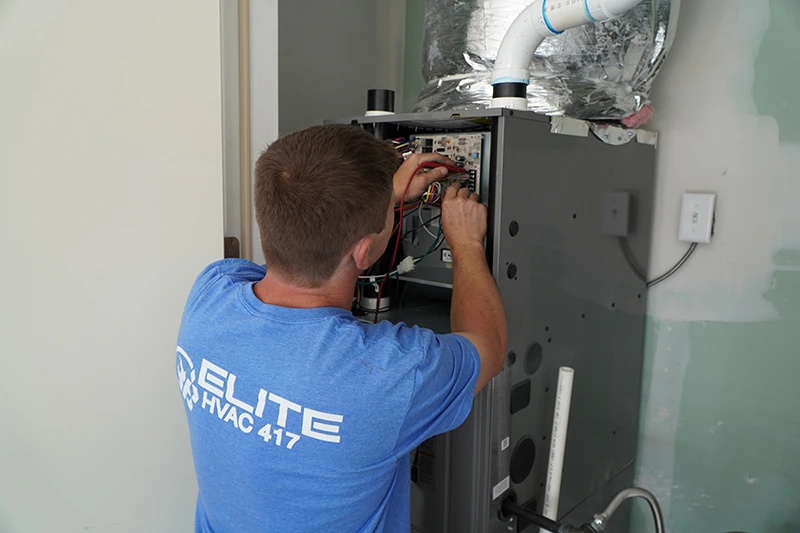 1 blue furnace worker Elite HVAC 417 technician performing furnace repair and maintenance service.